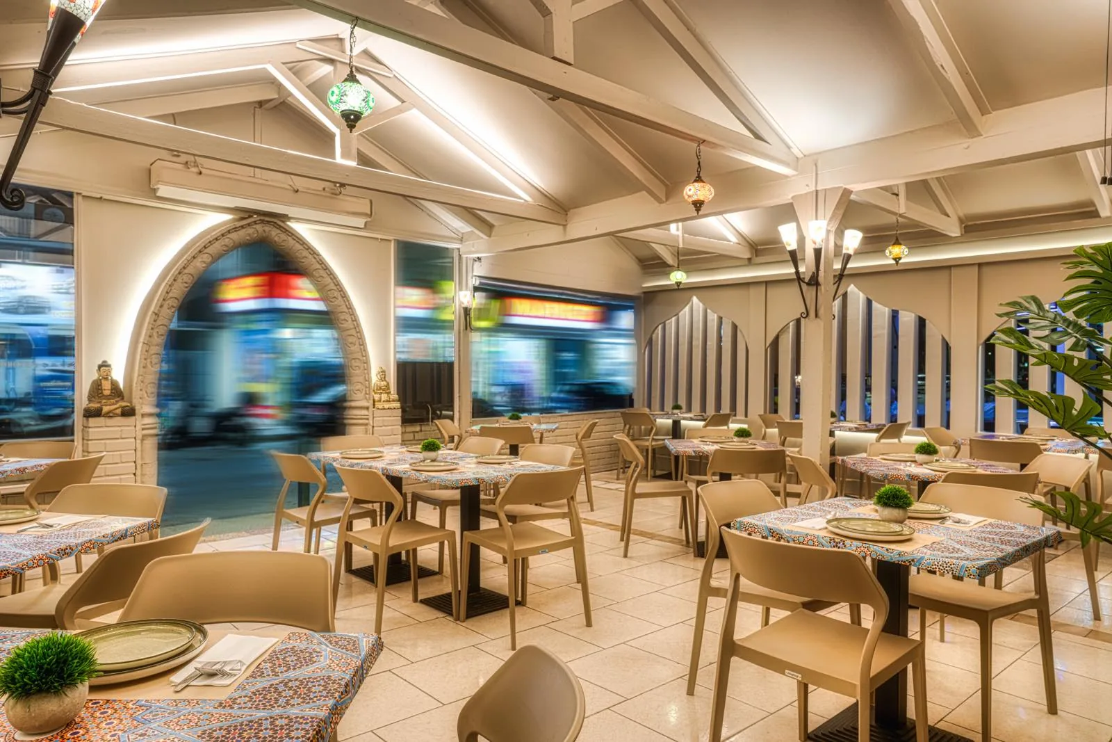 Tij Mahal Indian restaurant — warm cove lighting along the timber roof and a backlit carved arch, Athens